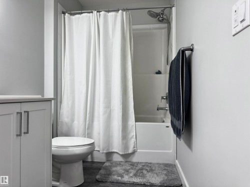 Full bathroom featuring a white tub/shower combination, polished chrome fixtures, and a light gray vanity with cabinet storage - 7432 Elmer Road, Edmonton, AB 