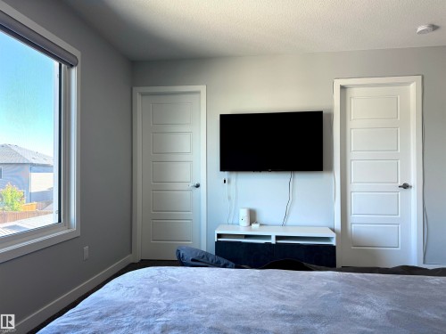 Bright interior space with a large window, light-colored walls, and two paneled doors - 7432 Elmer Road, Edmonton, AB 