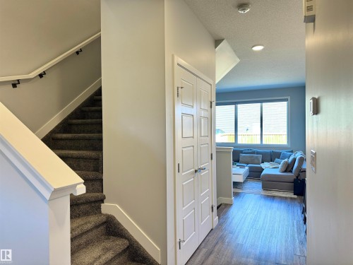 Foyer featuring panel doors, wood-finish flooring, and a carpeted staircase with white newel post and handrail - 7432 Elmer Road, Edmonton, AB 