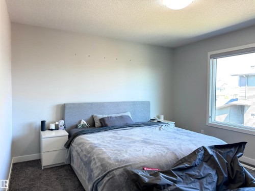 Carpeted room with a large window, a light-colored headboard, and neutral wall tones - 7432 Elmer Road, Edmonton, AB 