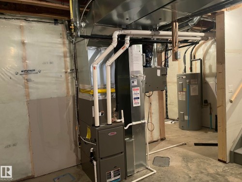 Utility space featuring a water heater, furnace, exposed ductwork, and unfinished walls - 7432 Elmer Road, Edmonton, AB 