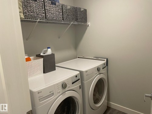 Dedicated laundry space featuring a white front-load washer and dryer set, wire shelving, and light gray wall paint - 7432 Elmer Road, Edmonton, AB 