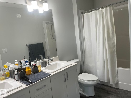 Contemporary bathroom featuring a double vanity with white cabinetry, integrated sinks, and chrome faucets - 7432 Elmer Road, Edmonton, AB 