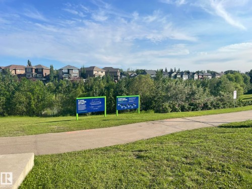 Paved pathway winding through a grassy area with mature trees and foliage - 7432 Elmer Road, Edmonton, AB 