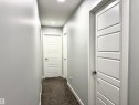 Hallway featuring light gray walls and dark carpeting - 7432 Elmer Road, Edmonton, AB 