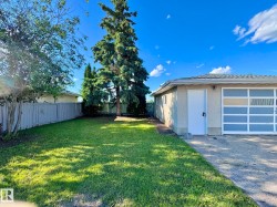 Spacious side yard featuring a manicured lawn, established trees, and a wooden privacy fence - 