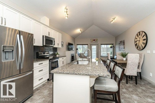 Open-concept kitchen and dining area featuring a vaulted ceiling and track lighting - 15 175 Mcconachie Drive, Edmonton, AB 