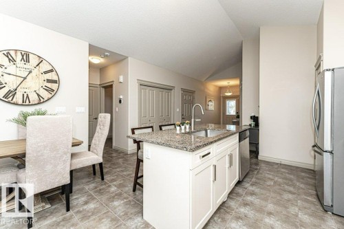 Kitchen island with a double basin stainless steel sink and granite countertop - 15 175 Mcconachie Drive, Edmonton, AB 