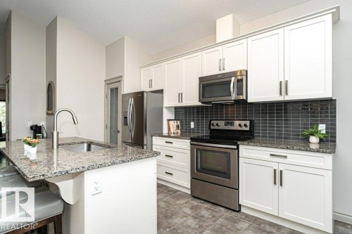 Modern kitchen featuring white cabinetry and stainless steel appliances - 15 175 Mcconachie Drive, Edmonton, AB 