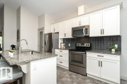 Modern kitchen featuring white cabinetry and stainless steel appliances - 