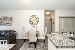 Open-concept living space featuring wood-finish flooring, light-toned walls, and a substantial kitchen island with a speckled countertop - 