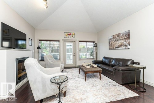 Living area featuring a vaulted ceiling, dark wood-finish flooring, a built-in fireplace, and a glass-paneled door - 15 175 Mcconachie Drive, Edmonton, AB 
