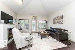 Living area featuring a vaulted ceiling, dark wood-finish flooring, a built-in fireplace, and a glass-paneled door - 