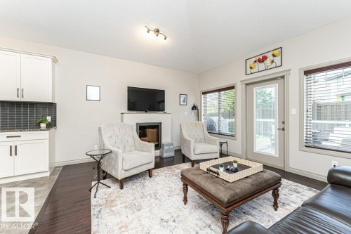 Living area featuring wood-finish flooring and a contemporary fireplace with a mounted television - 15 175 Mcconachie Drive, Edmonton, AB 