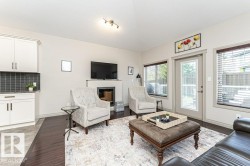 Living area featuring wood-finish flooring and a contemporary fireplace with a mounted television - 