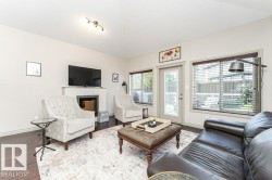 Living area featuring dark wood-finish flooring, light-colored walls, and a built-in fireplace with a television mounted above - 