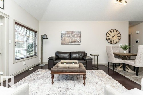 Open-concept living area featuring dark wood-finish flooring, light-toned walls, and a vaulted ceiling - 15 175 Mcconachie Drive, Edmonton, AB 