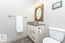 Bathroom featuring a white vanity with a granite-style countertop, undermount sink, and a rustic-framed oval mirror - 
