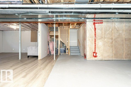 Spacious lower level featuring wood-finish flooring, exposed ceiling joists and ductwork, a partially finished area with white panel walls, and a concrete floor area - 15 175 Mcconachie Drive, Edmonton, AB 