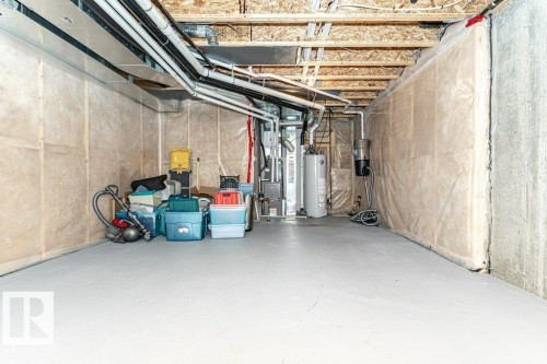 Unfinished basement space featuring a painted concrete floor, exposed joists, and utility access - 15 175 Mcconachie Drive, Edmonton, AB 