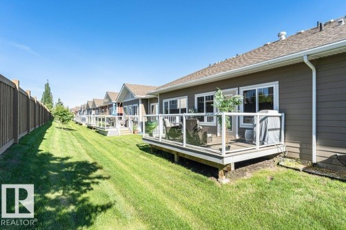 Rear exterior featuring a private deck with glass railing, durable horizontal siding, multiple windows, and a shingle roof - 15 175 Mcconachie Drive, Edmonton, AB 