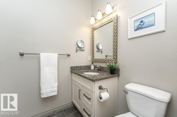 Bathroom vanity with granite countertop, integrated sink, and white cabinetry featuring brushed nickel hardware - 