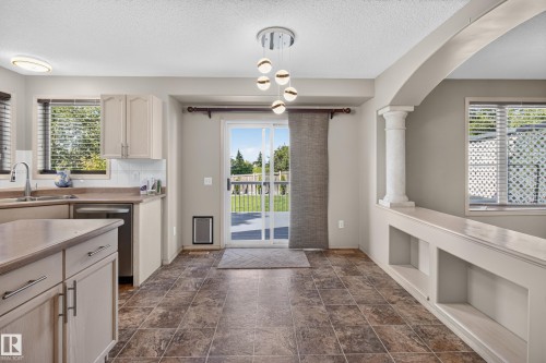 Kitchen area featuring neutral cabinetry, stainless steel dishwasher, and a white subway tile backsplash - 13406 32A Street, Edmonton, AB 