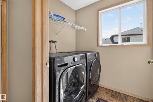 Dedicated laundry area featuring tile flooring and a window with wood-finish trim - 13406 32A Street, Edmonton, AB 