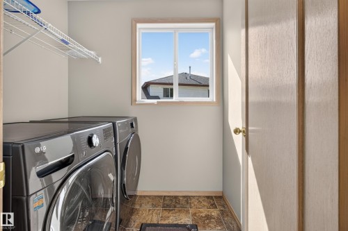 Dedicated laundry space featuring a window with natural light, wire shelving, and tiled flooring - 13406 32A Street, Edmonton, AB 