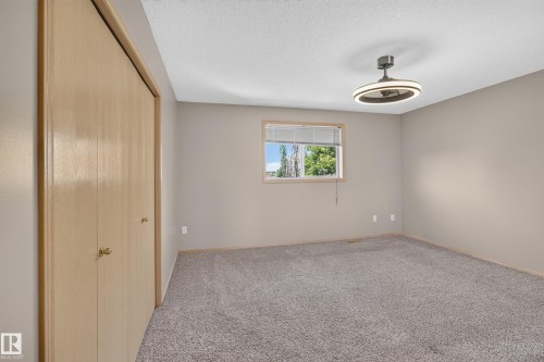Spacious room featuring neutral carpeting, light-toned walls, and a modern ceiling fan with integrated lighting - 13406 32A Street, Edmonton, AB 