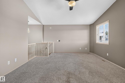 Spacious room featuring neutral carpeting, a ceiling fan with light fixture, and a window with blinds - 13406 32A Street, Edmonton, AB 
