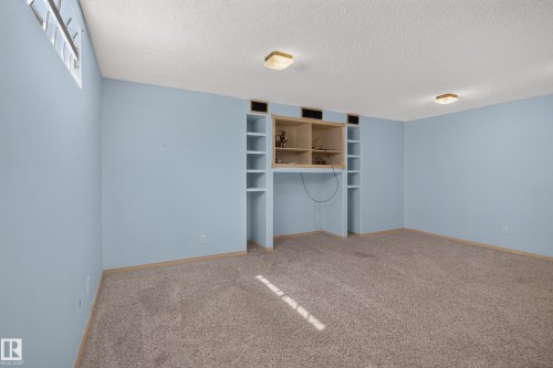 Carpeted room with a built-in media center featuring open shelving and a dedicated space for components - 13406 32A Street, Edmonton, AB 