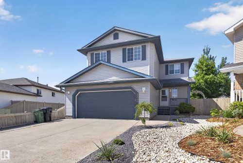Two-story residence featuring light gray siding, a dark gray garage door, and a concrete driveway - 13406 32A Street, Edmonton, AB 