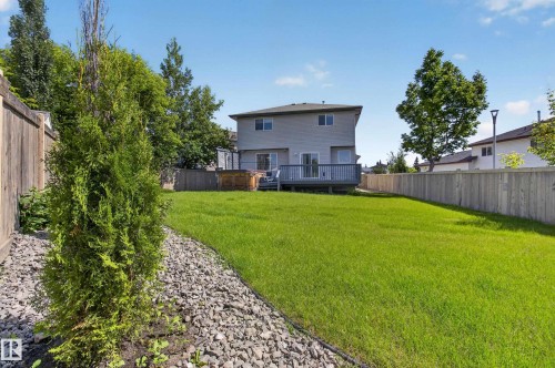 Expansive backyard featuring a spacious green lawn, a multi-level deck, and wood privacy fencing - 13406 32A Street, Edmonton, AB 