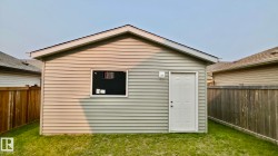 Detached outbuilding with light-colored siding and a gable roof - 