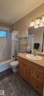 Bathroom featuring a single vanity with wood-finish cabinetry, an integrated sink, and a large wall-mounted mirror - 