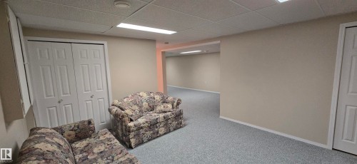 Spacious lower-level area featuring light-colored carpeting, neutral painted walls, and a drop-tile ceiling with recessed lighting - 4734 54A Avenue, Vegreville, AB - Indoor