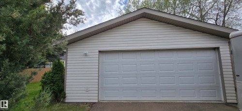 Detached garage featuring white horizontal siding and a panel-style garage door - 4734 54A Avenue, Vegreville, AB - Outdoor With Exterior