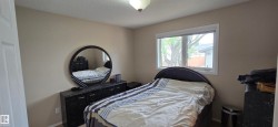 Bedroom featuring a neutral color palette, a ceiling-mounted light fixture, and a window with white trim - 