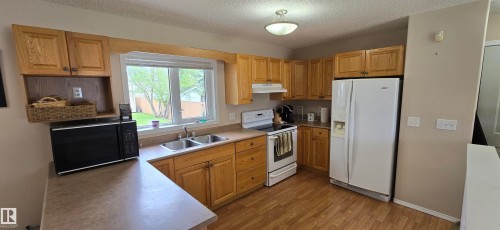 Kitchen featuring wood-finish cabinetry, laminate countertops, and stainless steel double basin sink - 4734 54A Avenue, Vegreville, AB - Indoor Photo Showing Kitchen With Double Sink