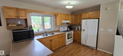 Kitchen featuring wood-finish cabinetry, laminate countertops, and stainless steel double basin sink - 