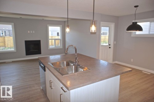 180 Radcliffe Wynd, Fort Saskatchewan, AB - Indoor Photo Showing Kitchen With Fireplace With Double Sink