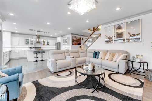Open-concept living space featuring wood-finish flooring, a contemporary chandelier, and recessed lighting - 656 180 Street Sw, Edmonton, AB - Indoor Photo Showing Living Room