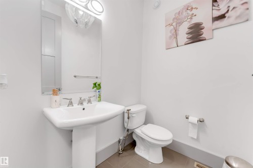 Pedestal sink with polished chrome fixtures, rectangular mirror, and ceiling-mounted light fixture - 656 180 Street Sw, Edmonton, AB - Indoor Photo Showing Bathroom