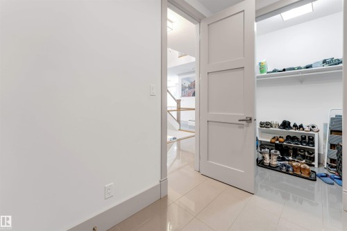 Recessed entryway storage featuring a three-panel interior door with brushed nickel hardware, light-toned tile flooring, and overhead lighting - 656 180 Street Sw, Edmonton, AB - Indoor Photo Showing Other Room