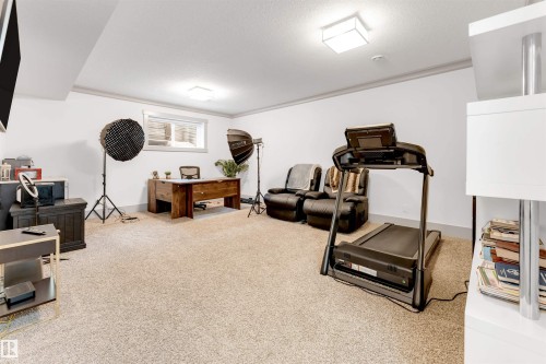 Carpeted room featuring recessed window, a built-in shelf unit, and two flush-mount ceiling lights - 656 180 Street Sw, Edmonton, AB - Indoor Photo Showing Gym Room
