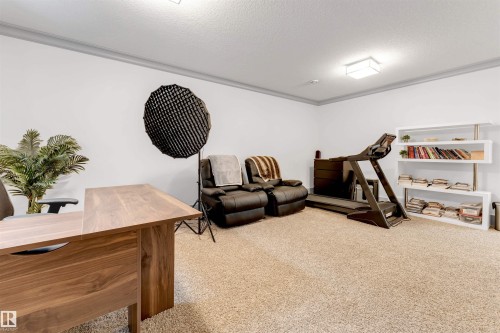 Carpeted room with white walls, crown molding, and a modern flush-mount light fixture - 656 180 Street Sw, Edmonton, AB - Indoor