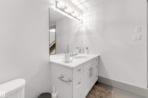 Vanity area featuring a white cabinet, integrated sink, and stone-finish countertop - 656 180 Street Sw, Edmonton, AB - Indoor Photo Showing Bathroom