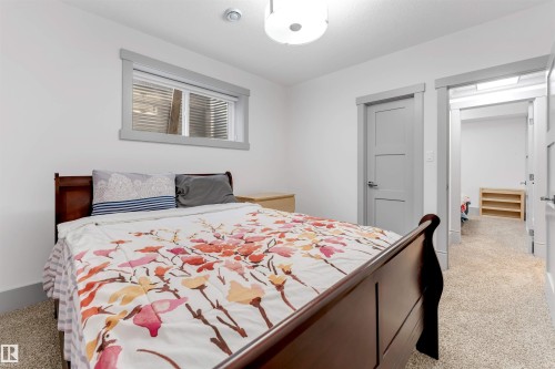 Carpeted bedroom featuring white walls, a wood-frame window with grey trim, a flush mount ceiling light, and a modern grey panel door - 656 180 Street Sw, Edmonton, AB - Indoor Photo Showing Bedroom