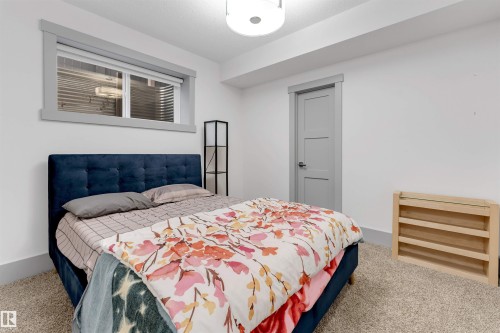 Carpeted room featuring a horizontal window with grey trim, a grey door with three recessed panels, and a flush-mount ceiling light - 656 180 Street Sw, Edmonton, AB - Indoor Photo Showing Bedroom